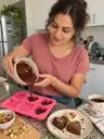 Escena ilustrativa: mujer preparando cápsulas de chocolate en un molde de corazón